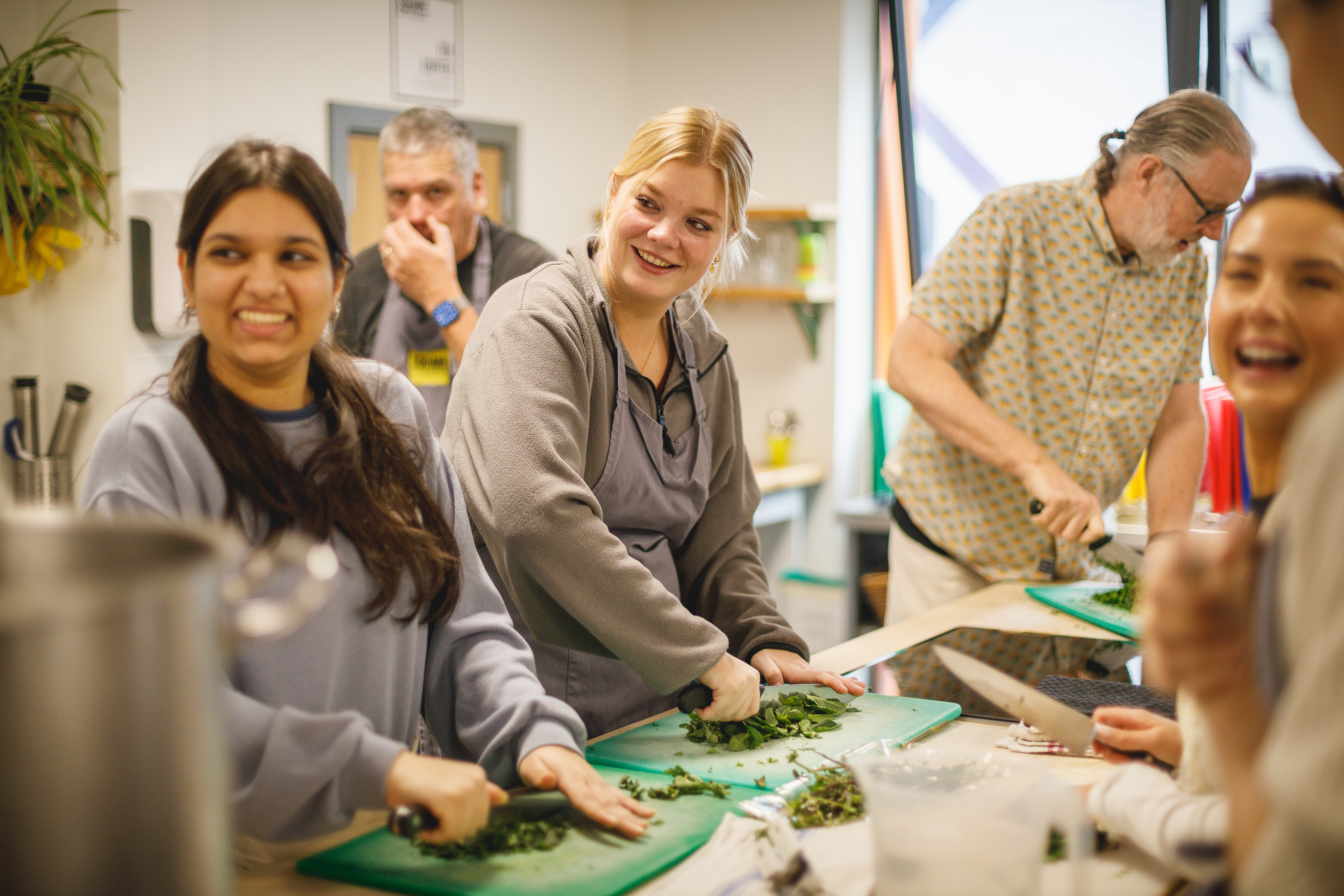 Happy group of adults chopping herbs in kitchen.jpg