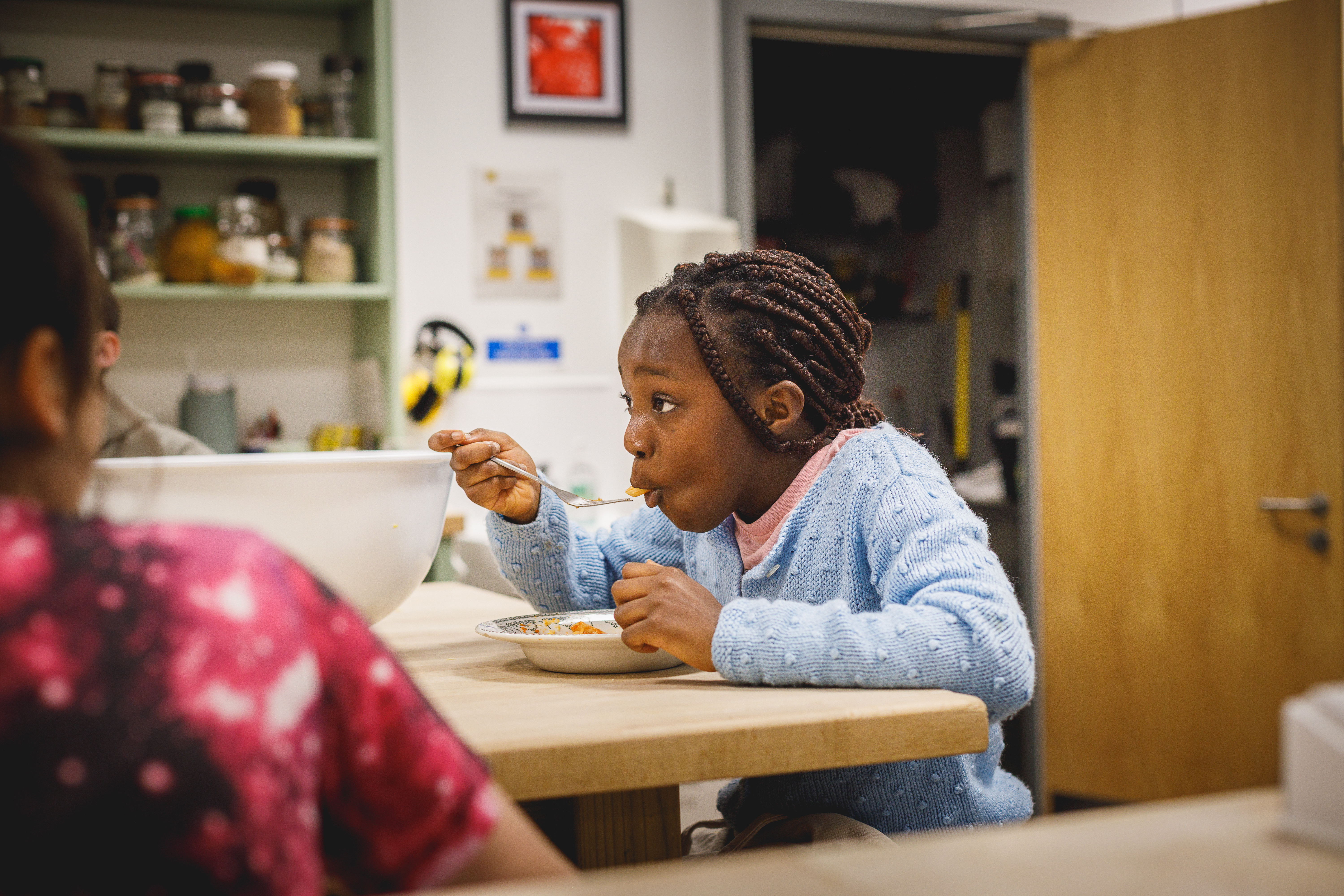 Young girl in blue jumper eating meal at table.jpg
