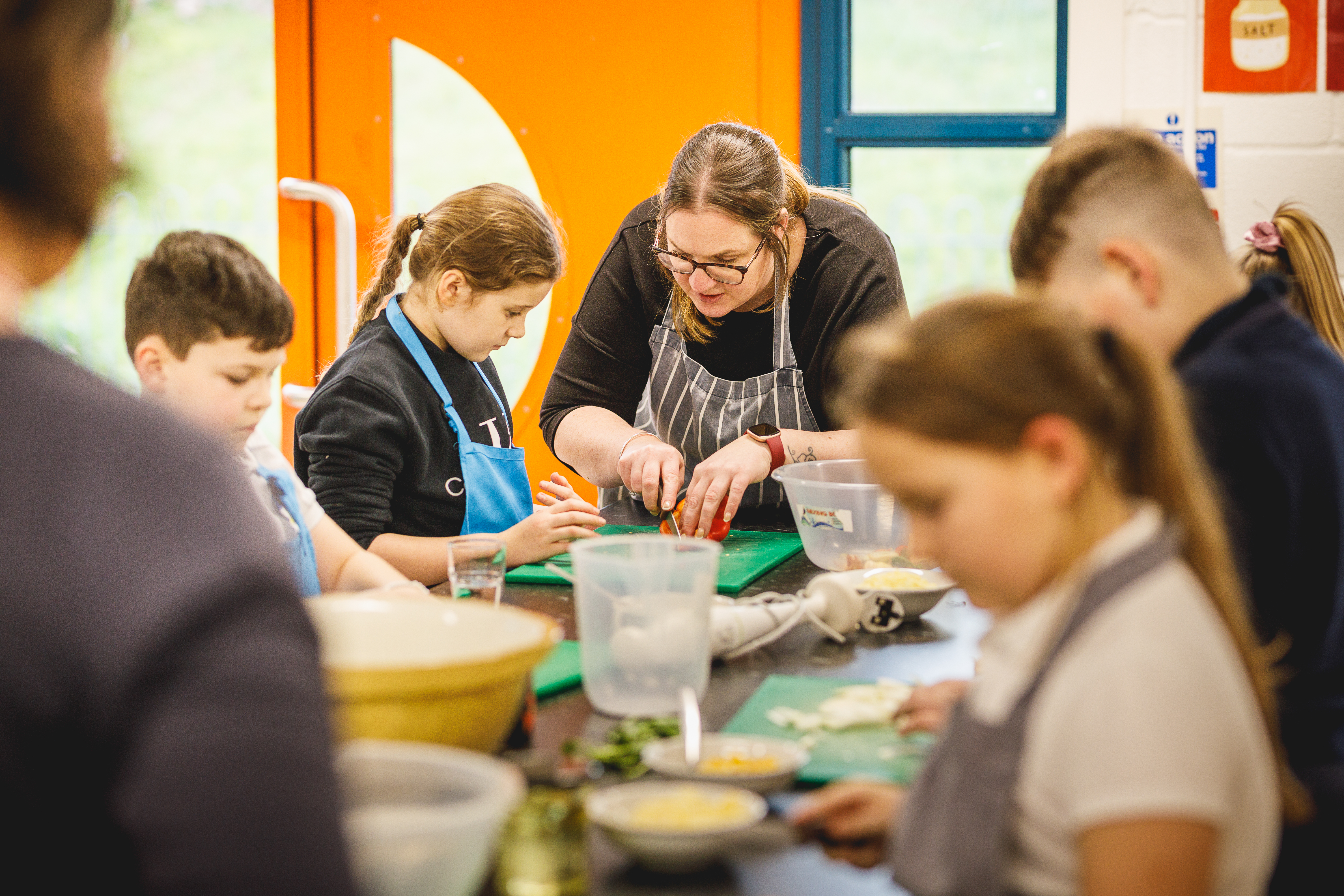 Teacher with a class of students learning to cook.jpg
