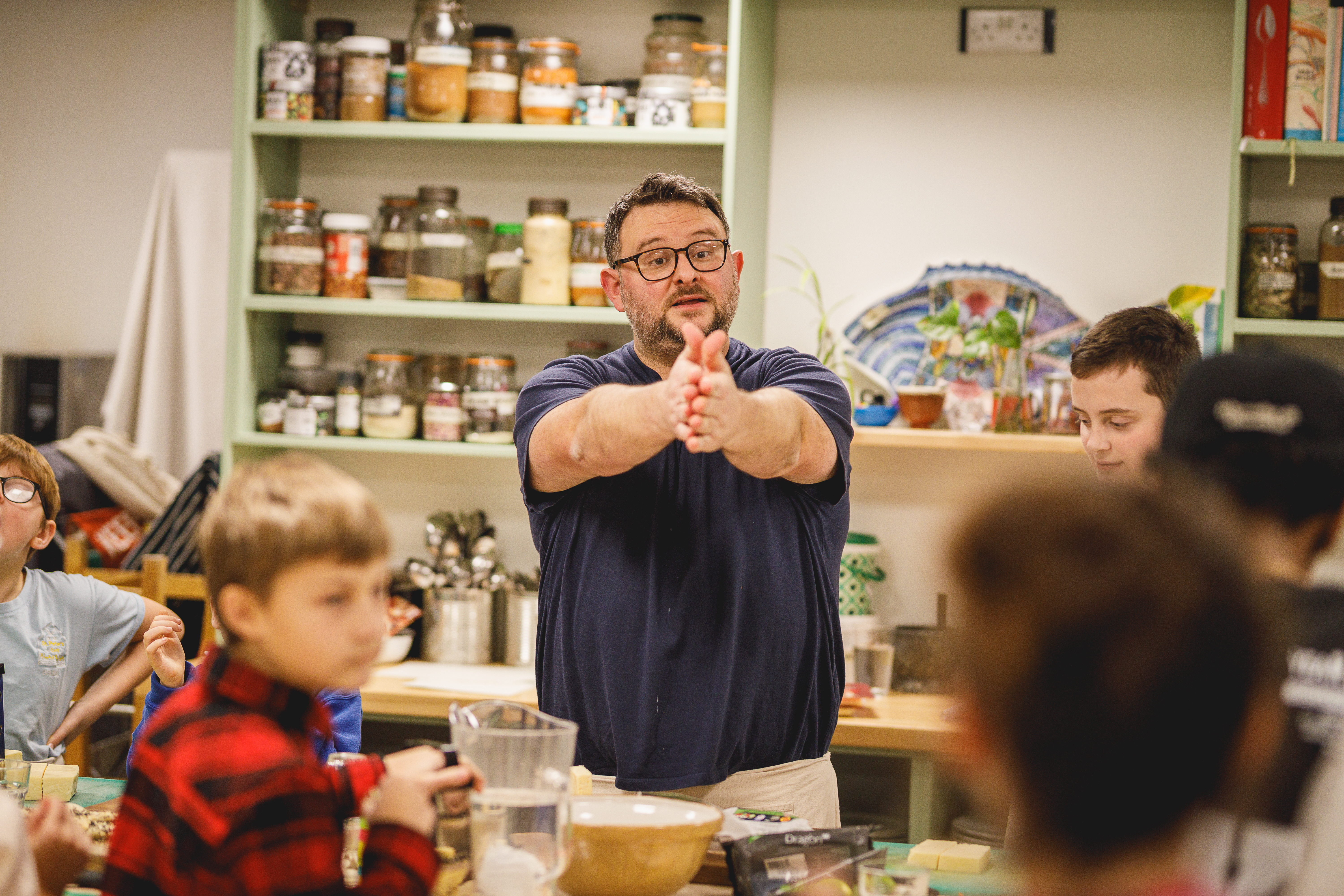 Cookery teacher Dan talking dynamically in front of classroom of children.jpg