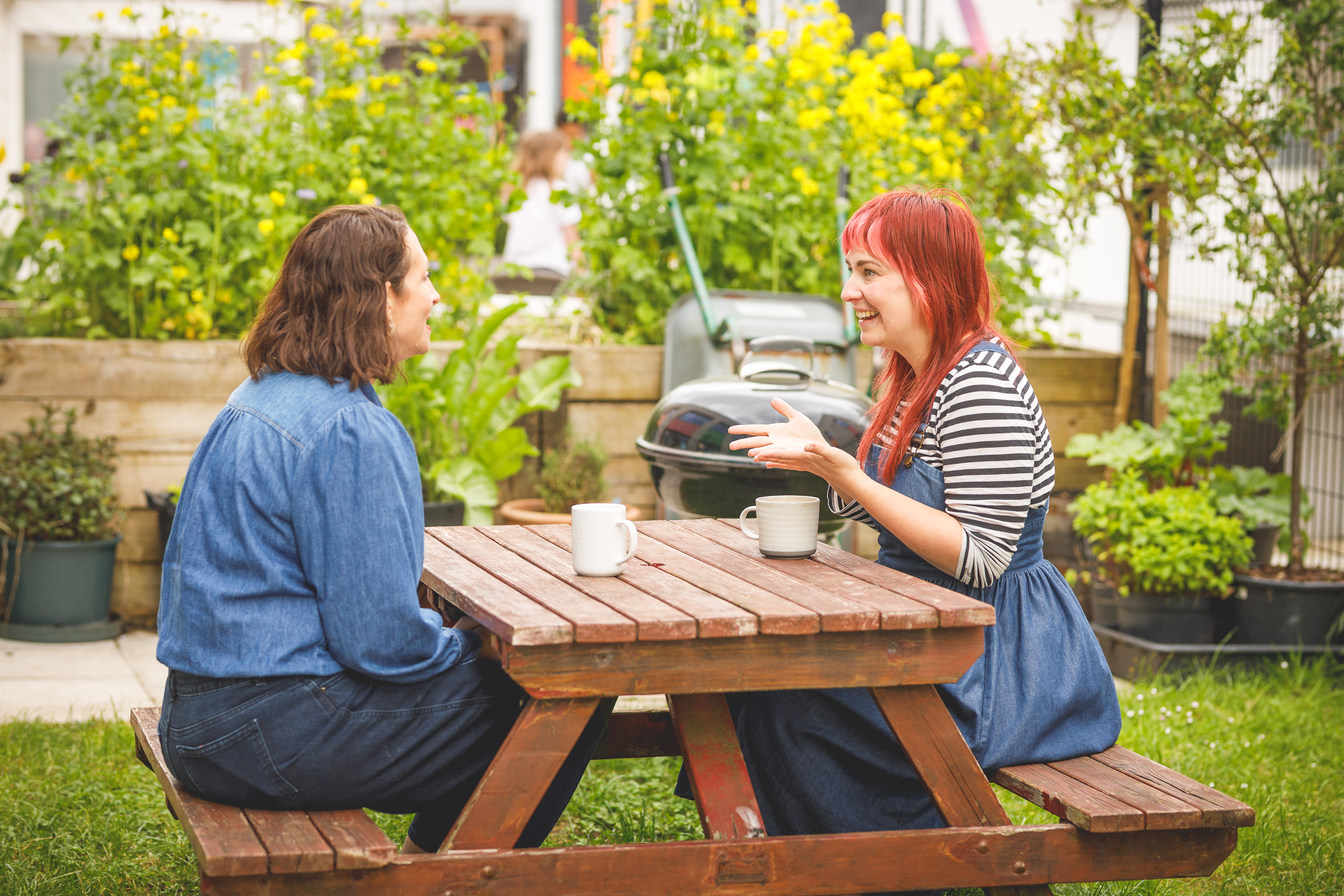 Two women at a picnic table talking together.jpg