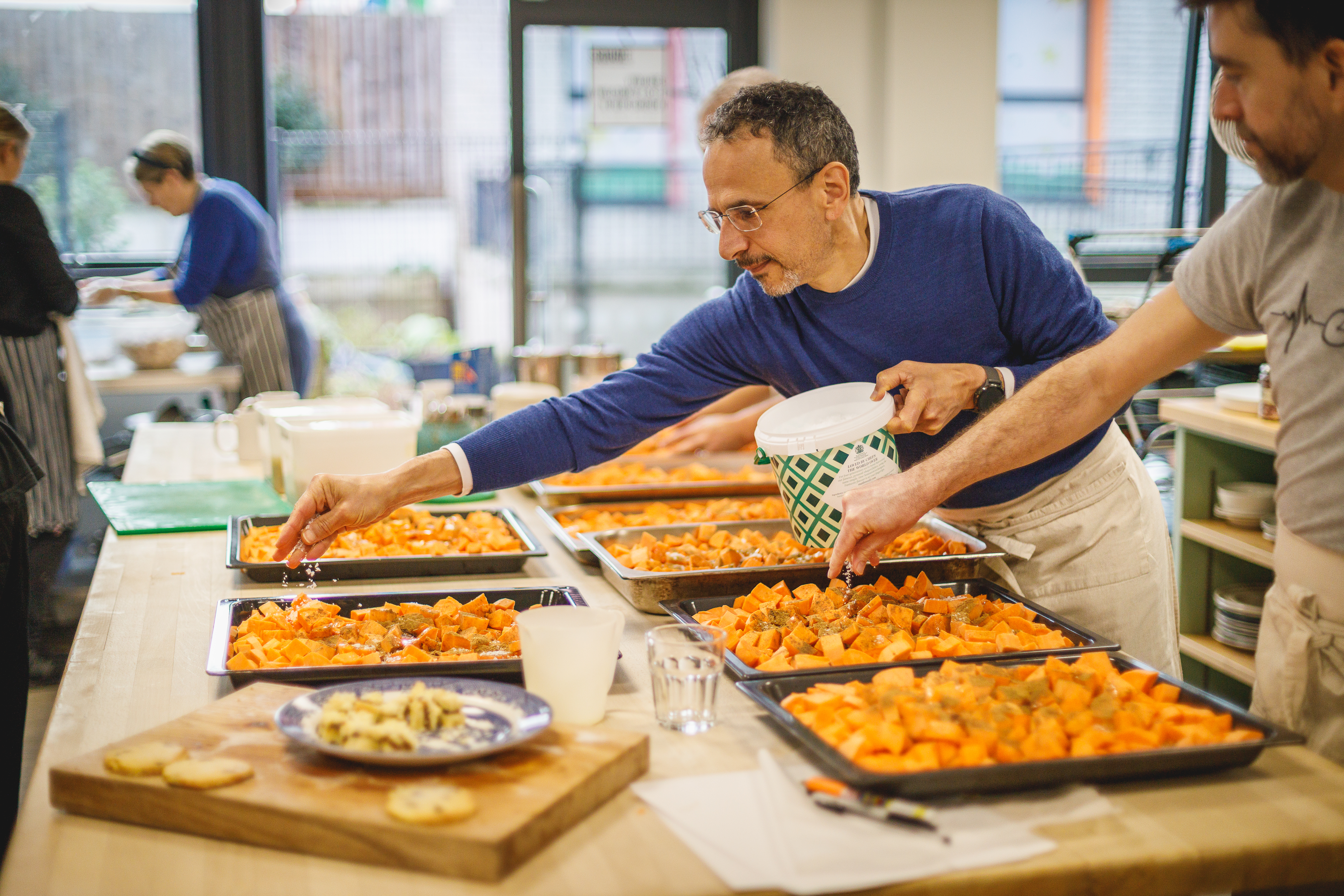 Two people adding salt to trays of sweet potatoes.jpg