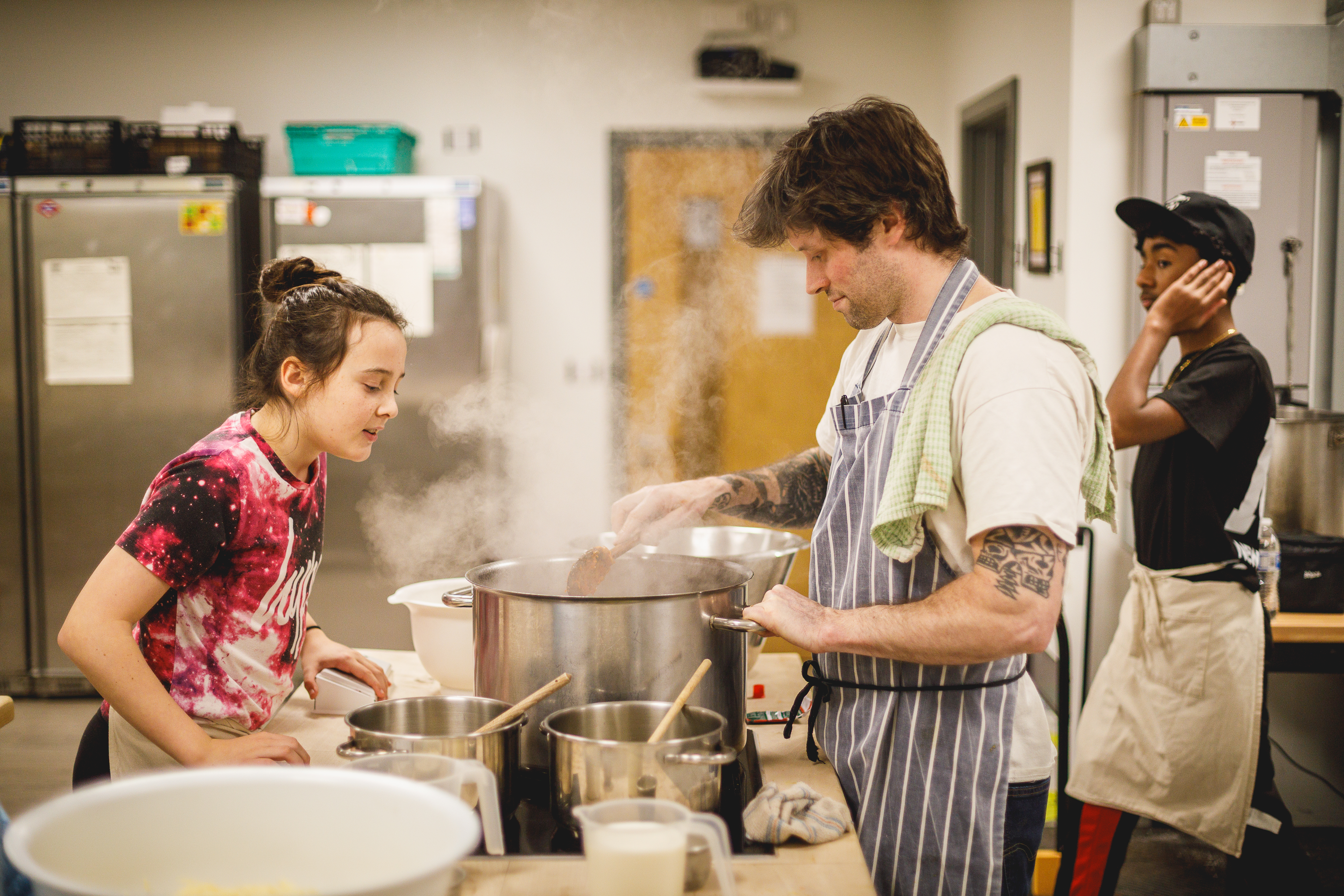 Cookery teacher Jesse and child looking into a large silver pan.jpg