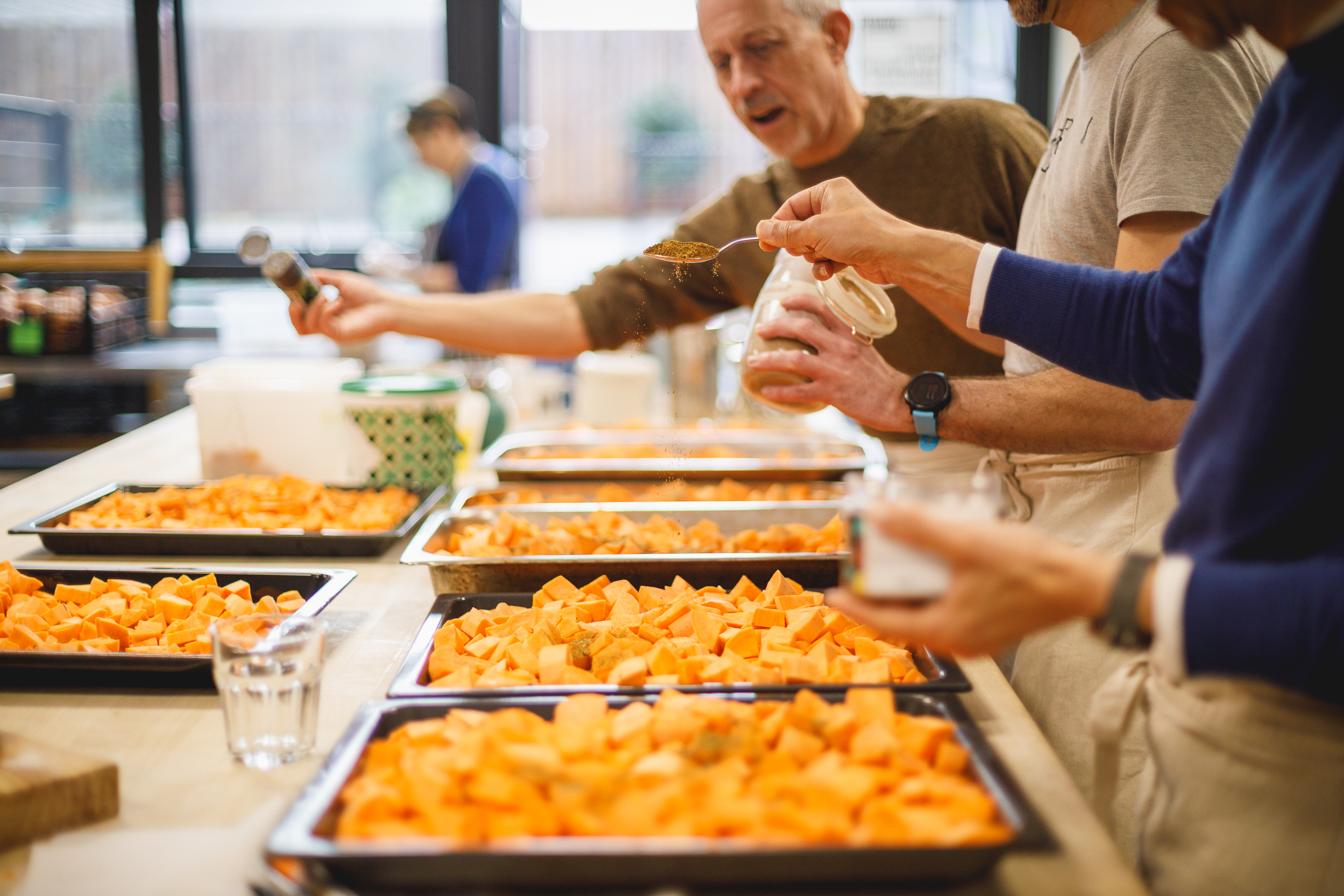 Group of people preparing trays of chopped sweet potato in the kitchen.jpg
