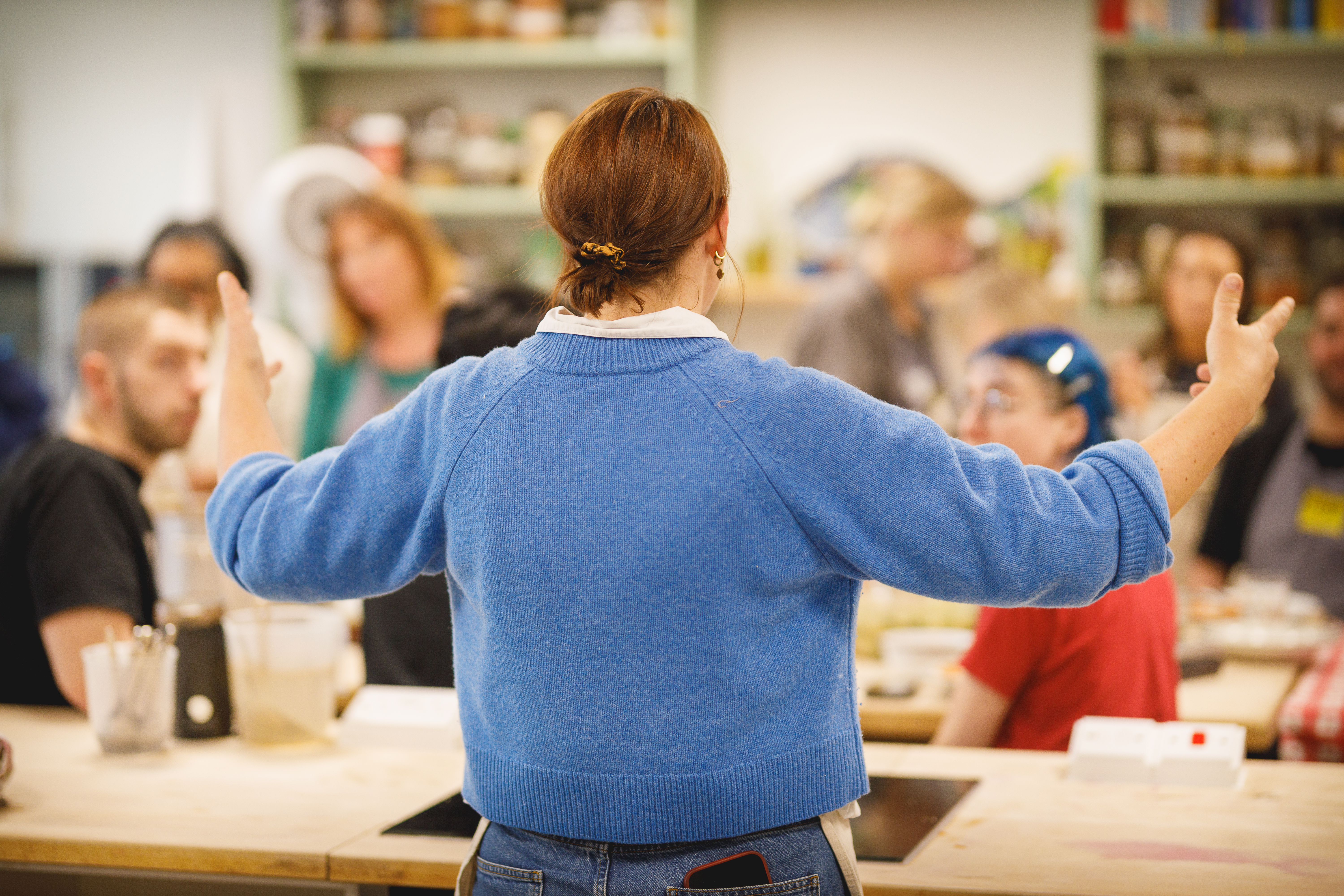 Teacher with her back to the camera teaching a class of interested people.jpg