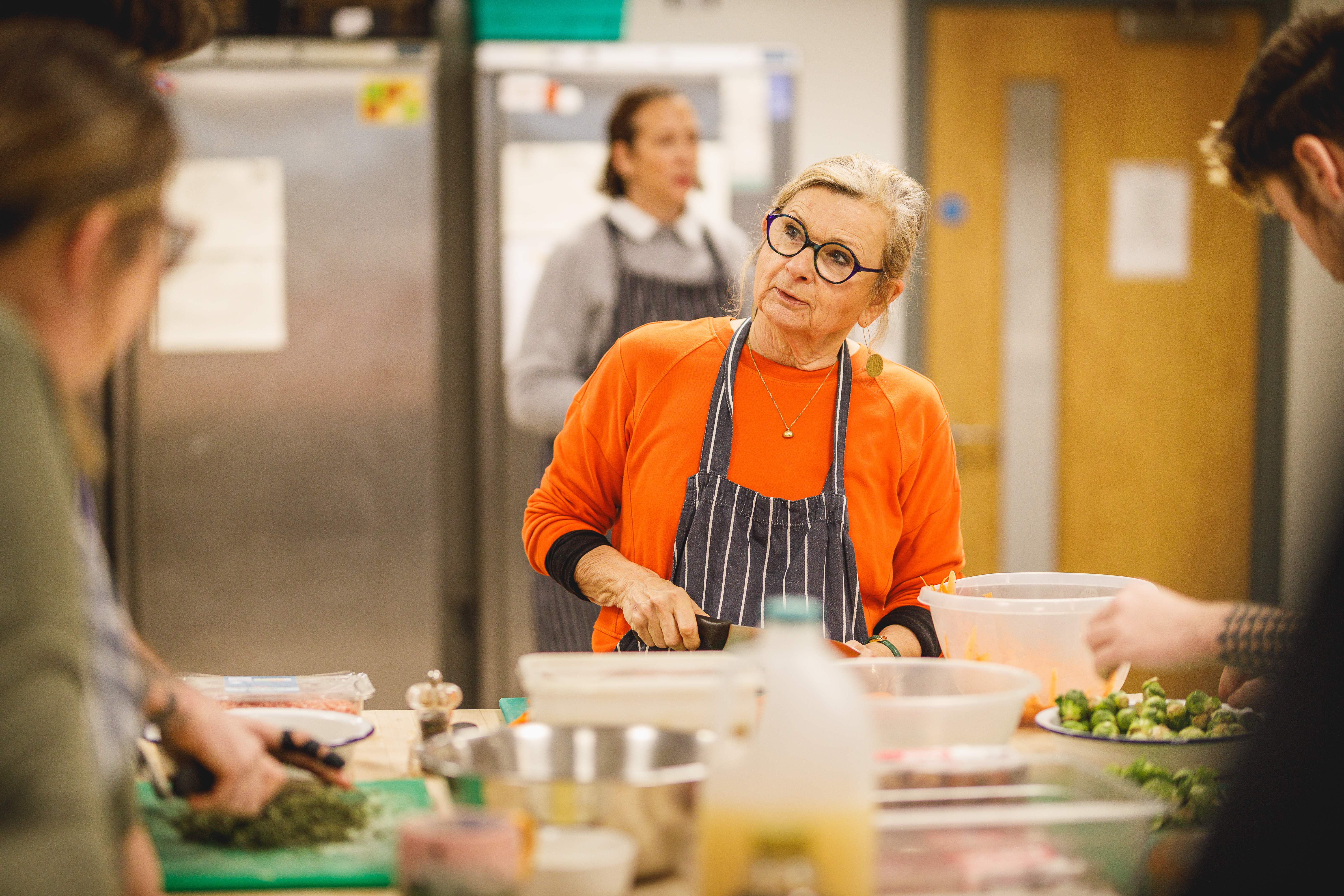 Woman in an orange jumper and glasses chopping ingredients.jpg
