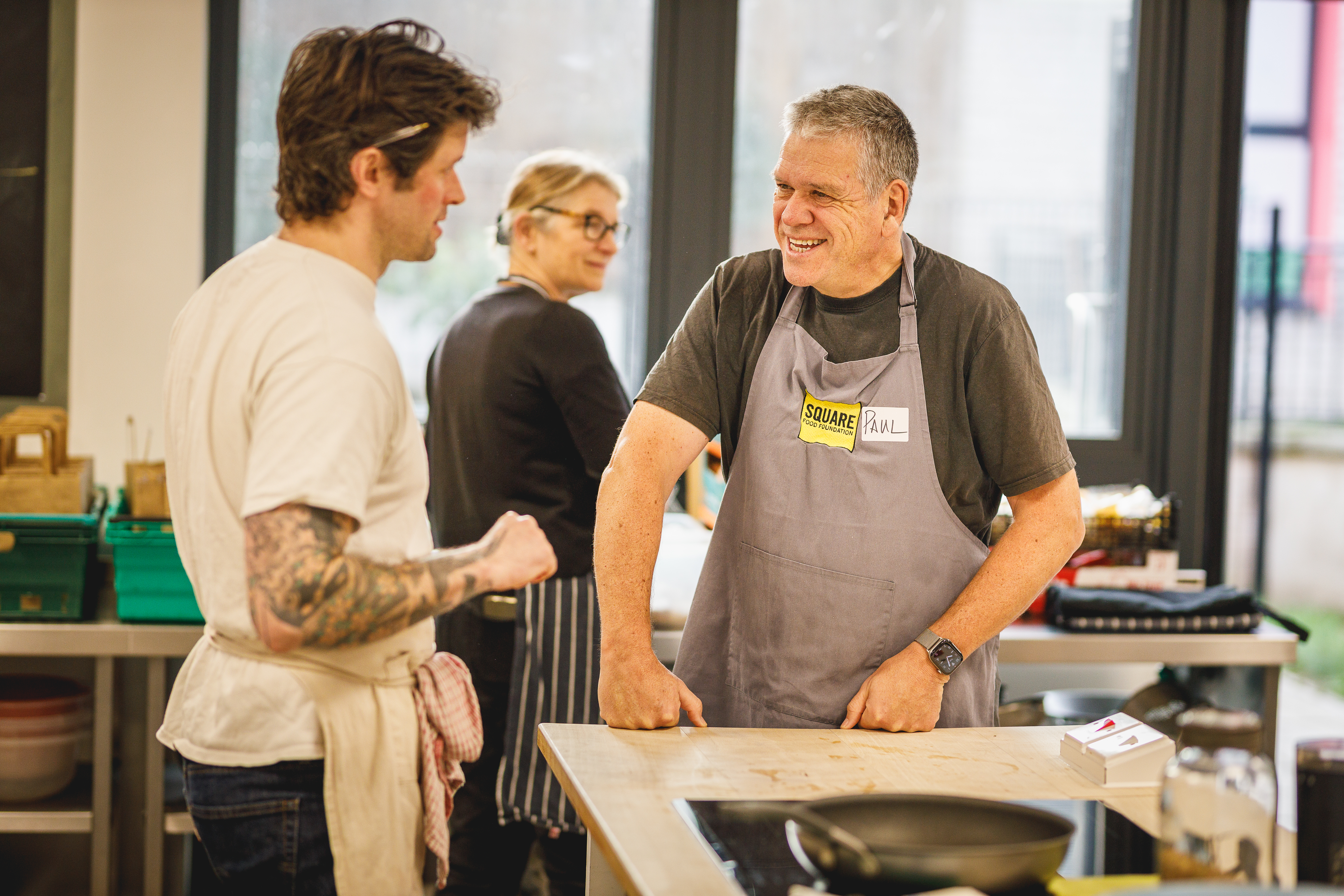 Teacher Jesse chatting to a volunteer in the cookery kitchen.jpg