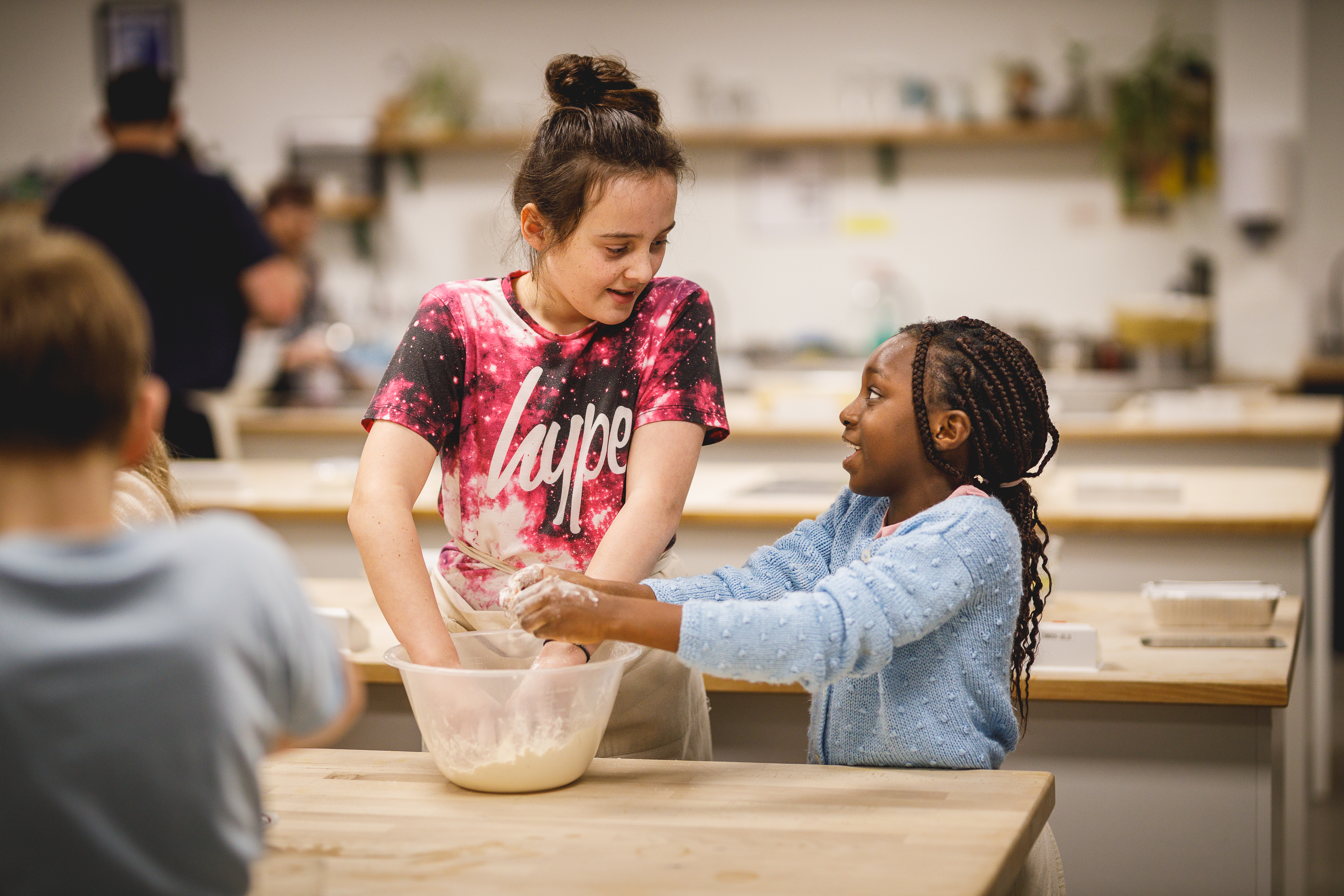 Two girls of different ages with hands in a mixing bowl.jpg